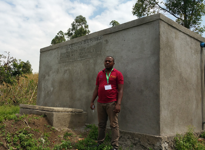 Dr. Bwema and water tanks constructed at the Bulenga Clinic.
