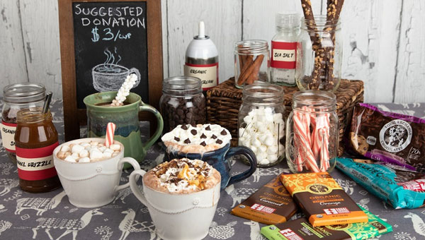 A hot cocoa bar set up with cups of cocoa and all the possible toppings