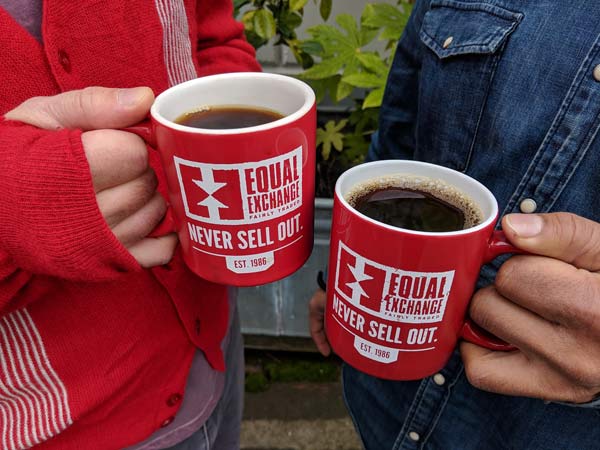 two people holding red coffee mugs