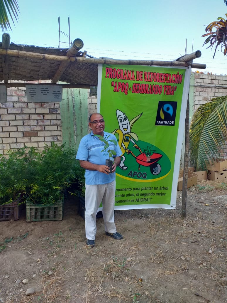 Banana farmer in front of APOQ banner